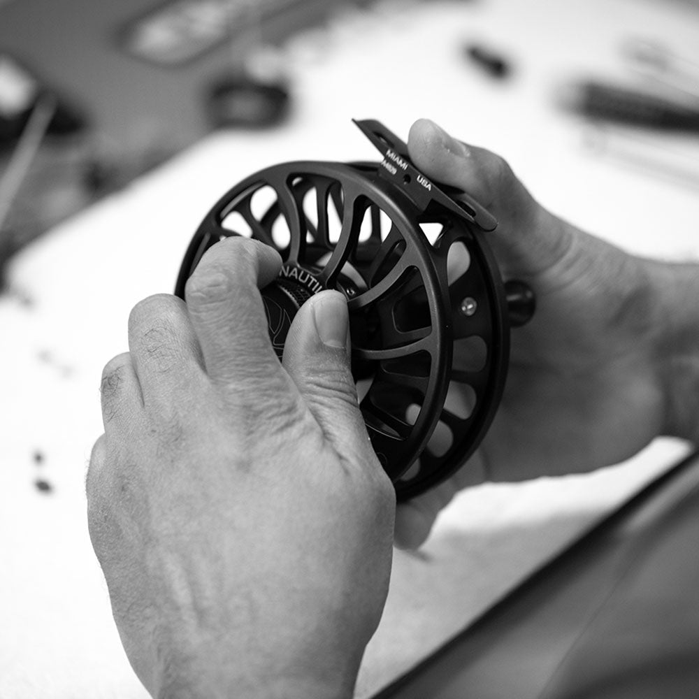 Person holding a fly fishing reel with a blurred background